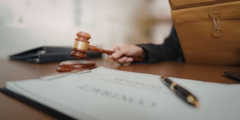 Judge's gavel resting near a contract and pen on a polished desk, hinting at a legal decision moment.